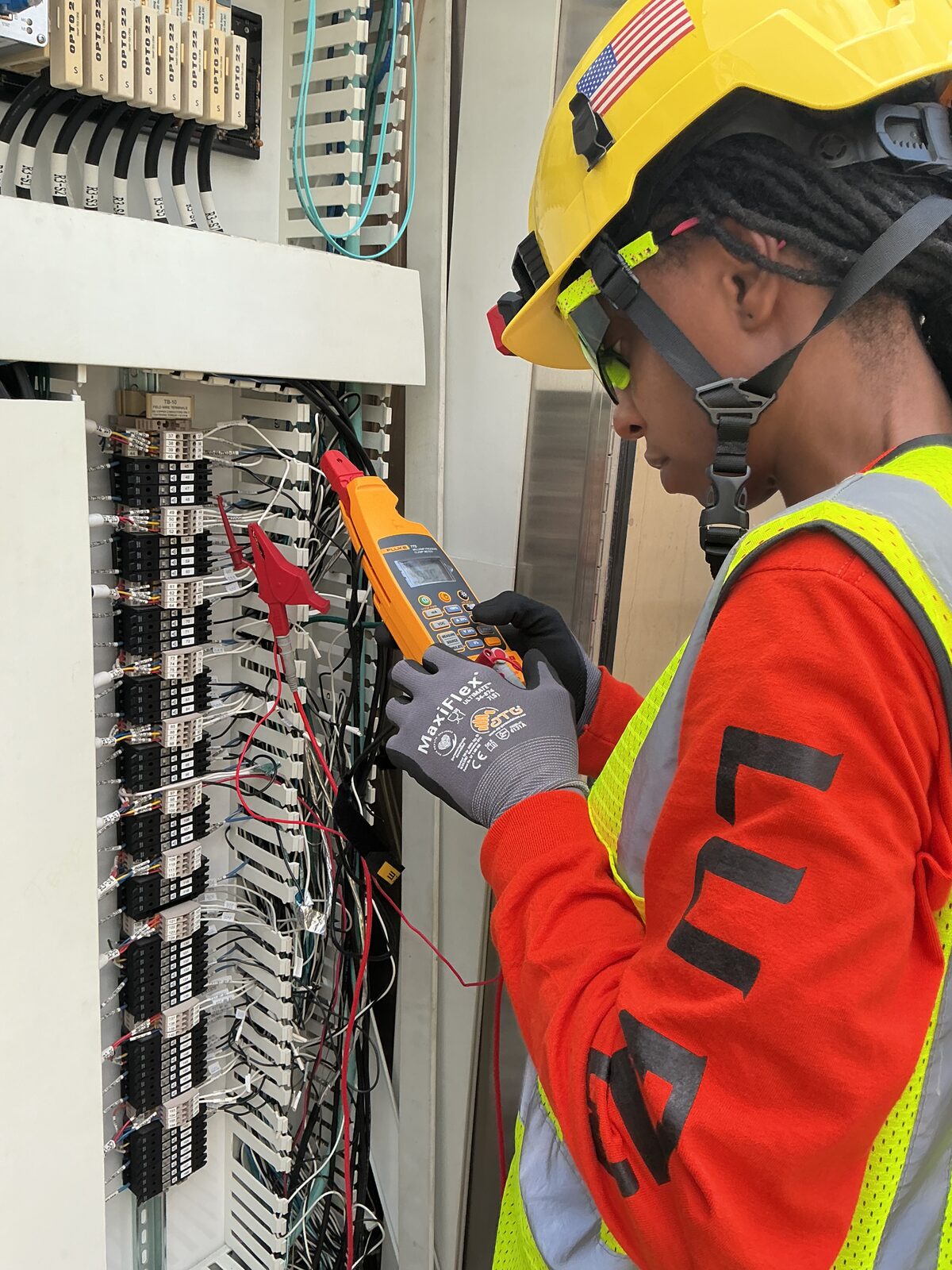 Close view of a milliamp process clamp meter connected to labeled field terminals inside an industrial control panel