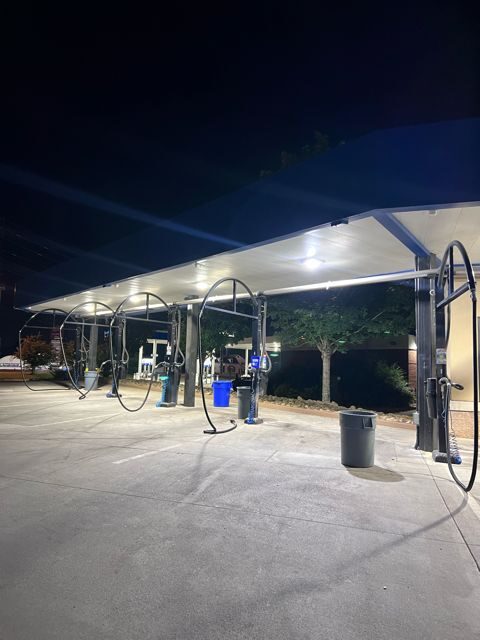 Covered canopy lit by bright LED fixtures over a row of vacuum stations at night
