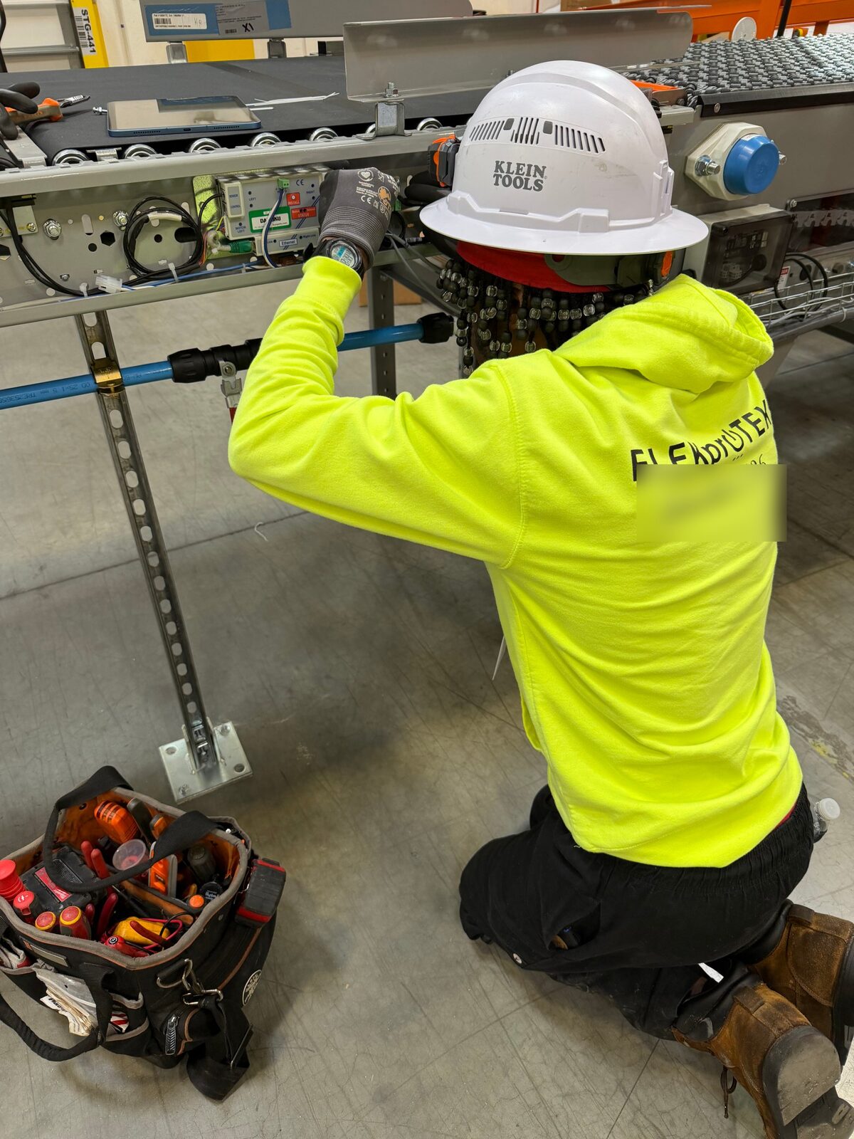 ELEKproTEK electrician in a hard hat wiring and terminating controls on an automated conveyor sorter