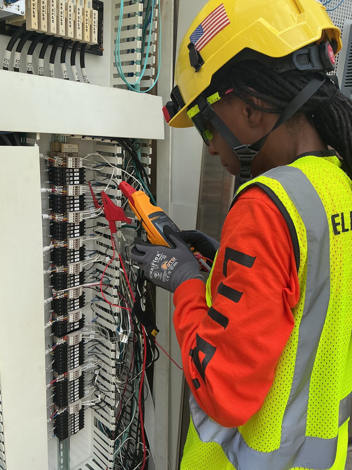 Electrician performing a loop check on a control panel with Opto 22 I/O modules using a Fluke milliamp process clamp meter