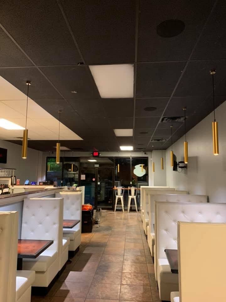 Restaurant dining room with gold pendant lights, ceiling light panels and white booth seating