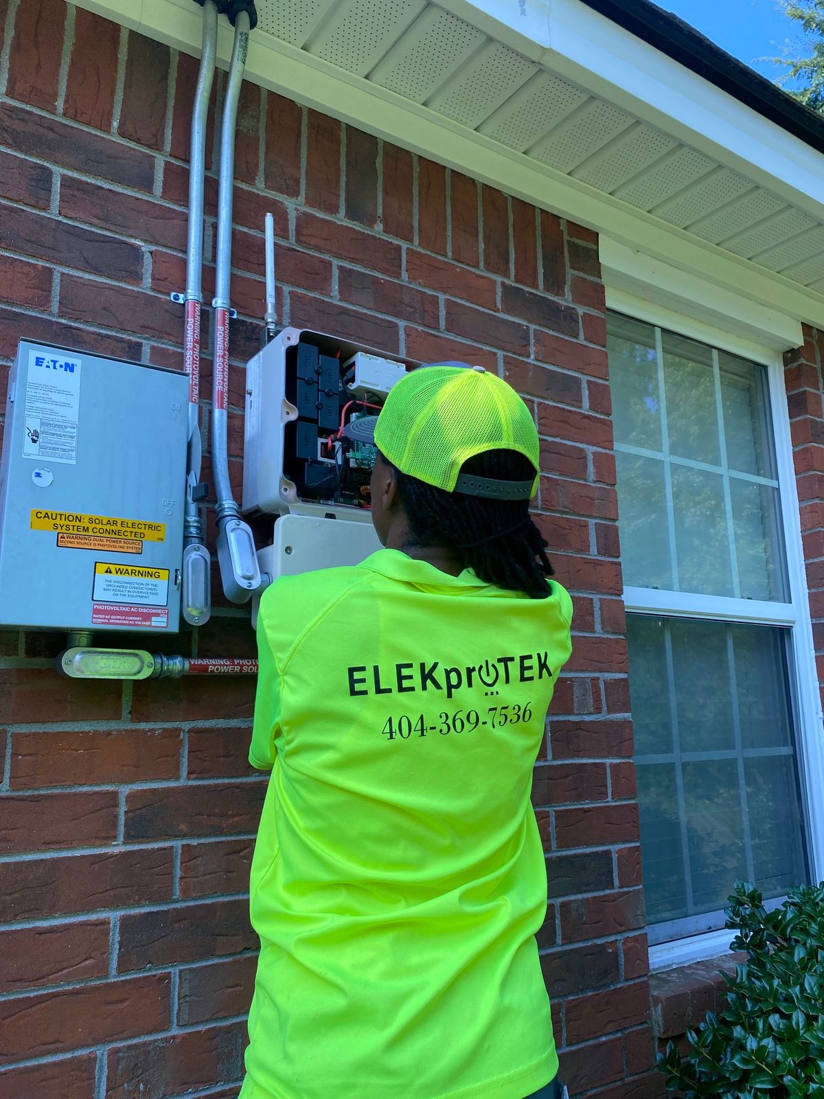 Technician working at a disconnect and meter base mounted on a brick wall