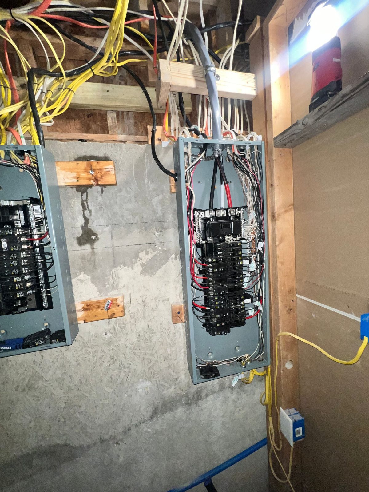 Utility closet with two open breaker panels and many cables entering from above
